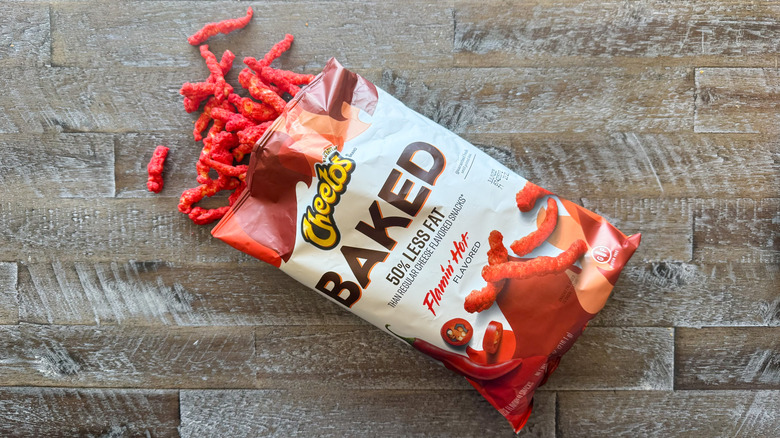 Cheetos baked Flamin' Hot chips bag with chips spilling out on wooden surface