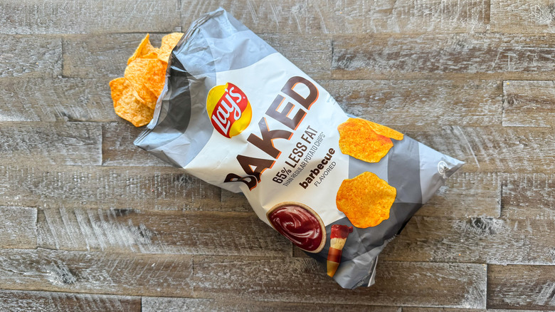 Lay's baked barbecue potato chips bag with chips spilling out on wooden surface
