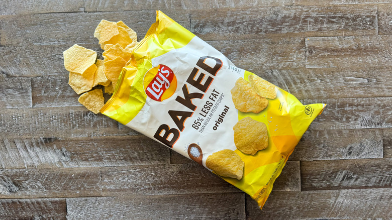 Lay's baked original potato chips bag with chips spilling out on wooden surface