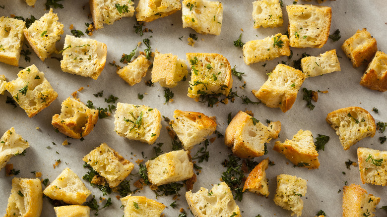 Crispy, herb-coated croutons on a parchment-lined baking sheet