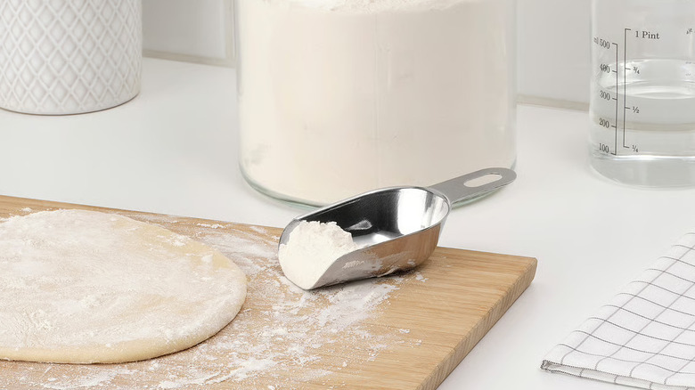A small metal scoop on a floured cutting board with dough