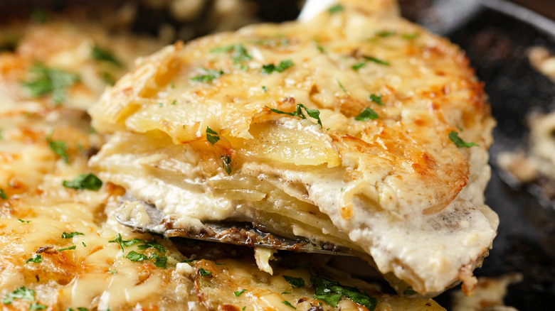 potatoes au gratin being scooped out of a baking dish