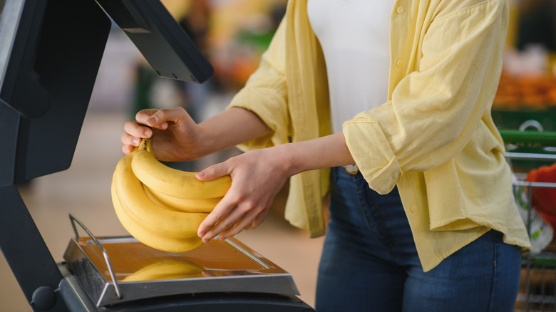 Woman placing a bunch of bananas on a scale in the store