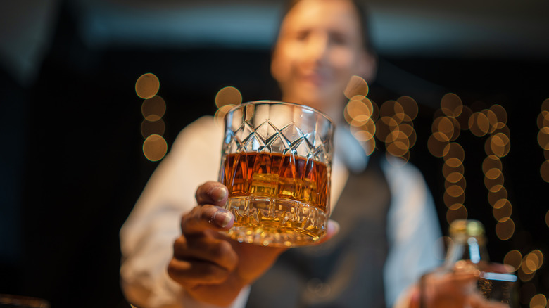 Blurry bartender handing a drink to camera