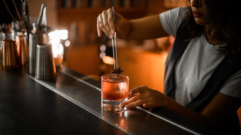Bartender putting star anise in a drink