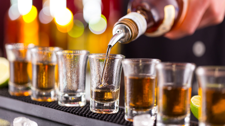 Bartender's hand pouring a line of shots