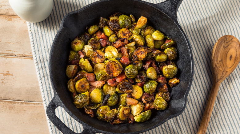 Brussels sprouts fried crisp in a pan with bacon in a cast iron skillet