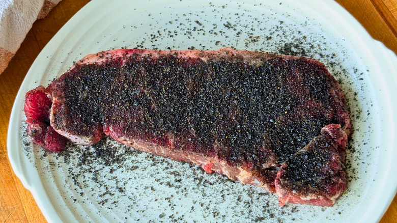 Raw steak covered in charcoal dry rub
