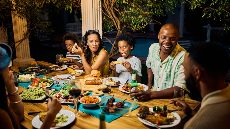African-American family gathered around a table with grilled meats and a selection of side dishes