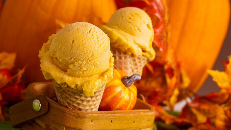 Ice cream cones with autumn leaves and pumpkins in the background