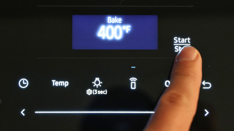 finger pressing the start button on an oven screen set to 400 F
