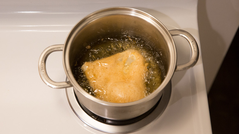 breaded fish frying in pot