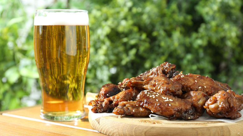 A glass of beer and plate of chicken wings