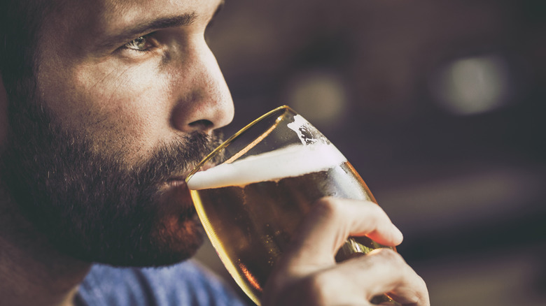 Close-up of man thoughtfully drinking beer from a glass