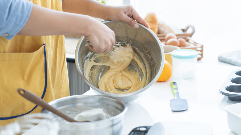 A person in a yellow apron mixing ingredients for a cake