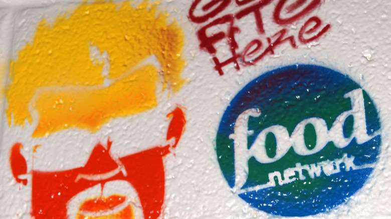 A signed brick at a restaurant Guy Fieri visited with spray painted pictures of his face and the Food Network logo