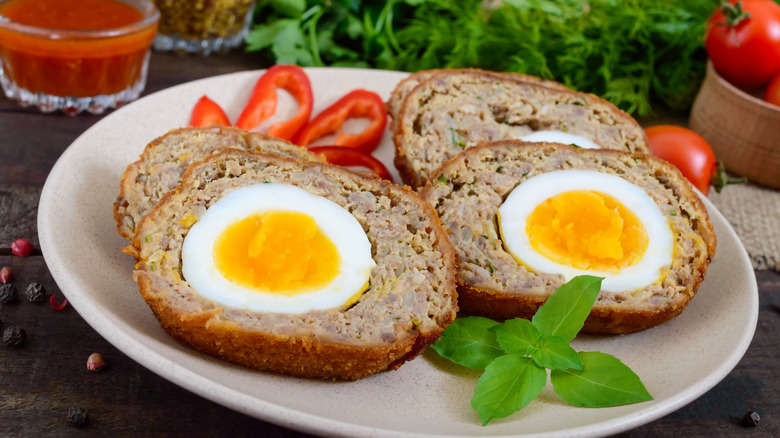 A plate has meatloaf with an egg baked into the middle.