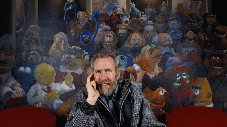 Jim Henson sits in front of a mural of many of the puppets he created, including those from Sesame Street.