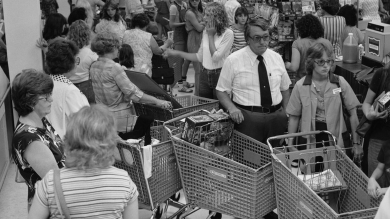A 1970s supermarket is crowded with people and shopping carts.