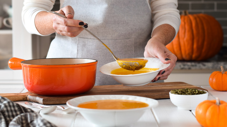 person ladling out pumpkin soup into bowls