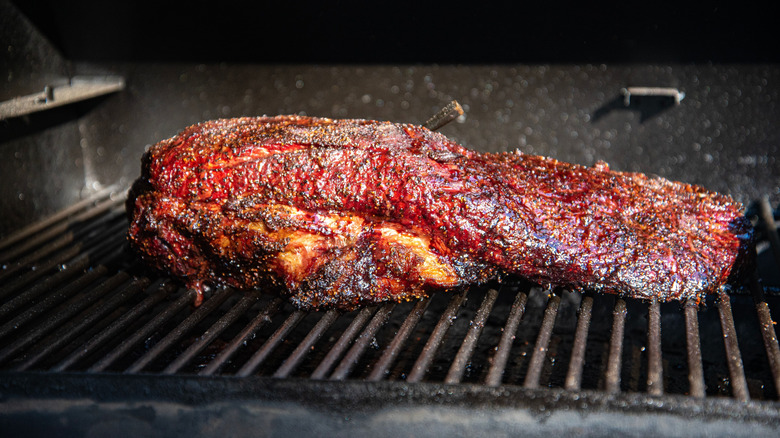 Seasoned brisket cooking on grill