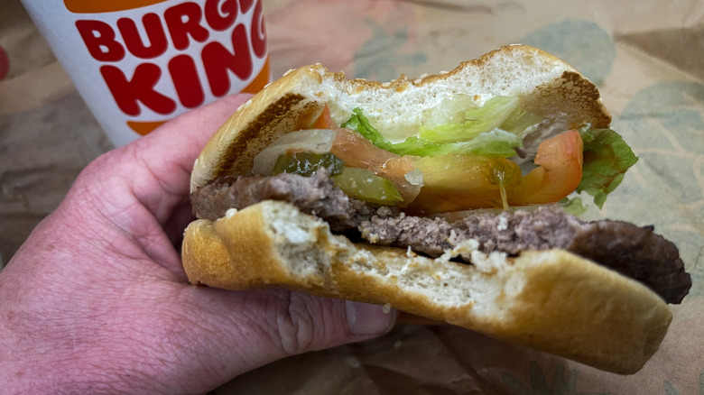Hand holding a bitten Burger King Whopper burger