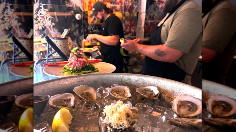 Scrag and Rind oysters displayed on ice with chefs in the background