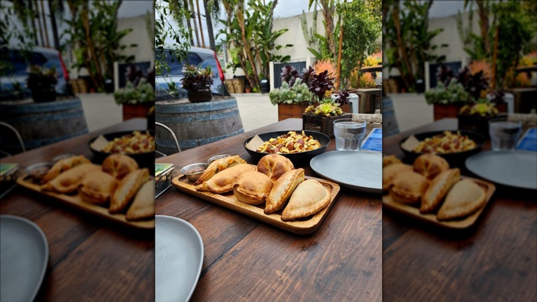 Plate of empanadas on a table within a picnic area filled with plants