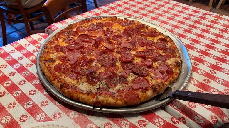Large pepperoni and ham pizza served on a metal platter