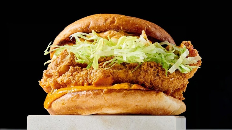 Fried chicken sandwich on a pedestal, stuffed with lettuce and sauce