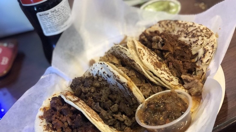 Plate of tacos alongside salsas and a Coca-Cola bottle