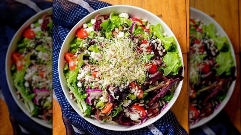 Vegan tomato feta salad in a bowl, topped with sprouts