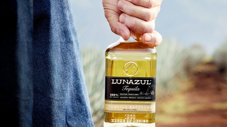 Hand holding a bottle of Lunazul Reposado outside