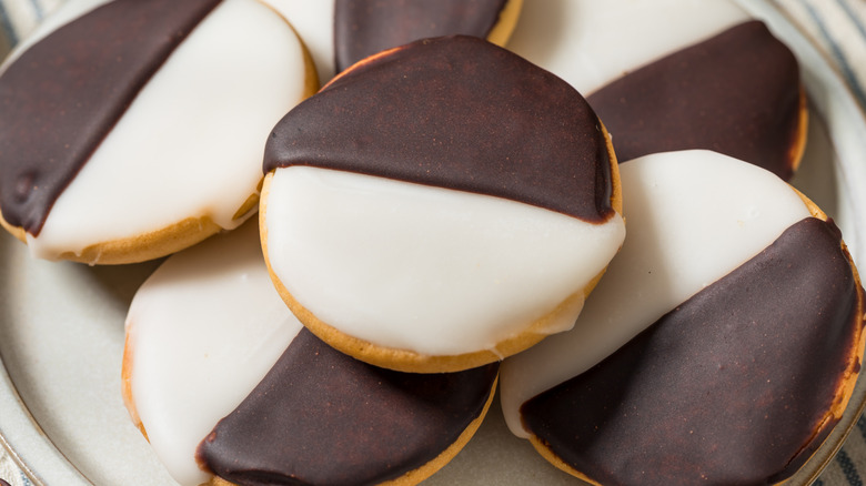 Several black and white cookies stacked on a plate