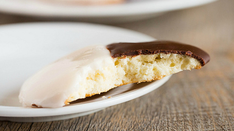 Close-up of a black and white cookie with a bite taken out of it to show the soft interior