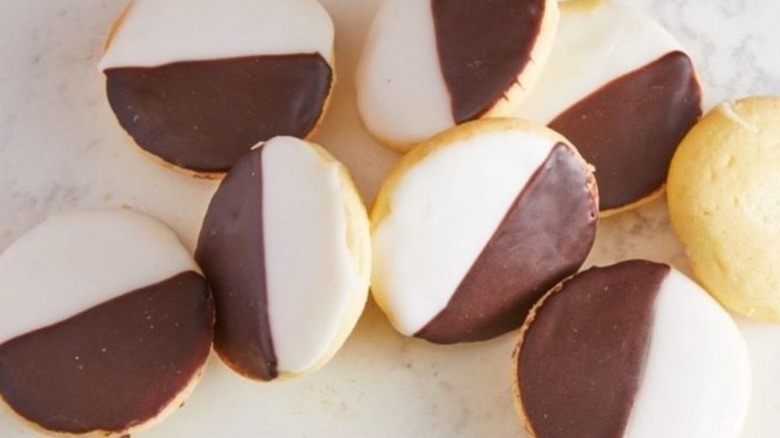 Overhead shot of eight black and white cookies scattered on a countertop