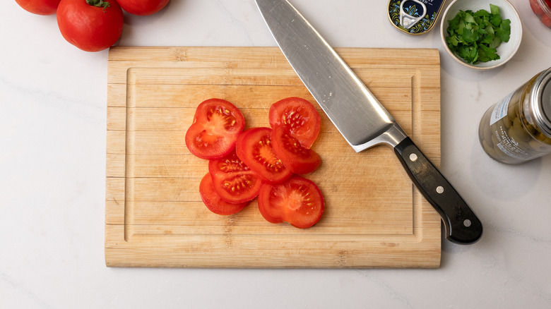 chopping tomatoes on board