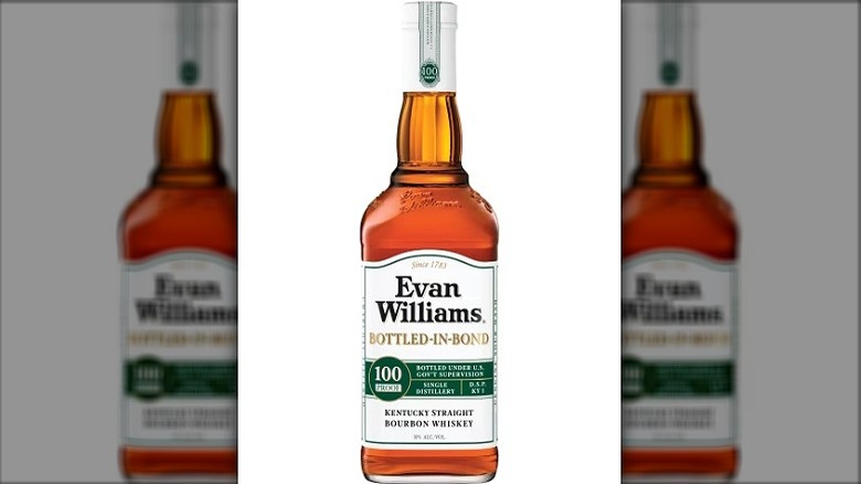A bottle of Evan Williams Bottled-in-Bond posed on top of a wooden barrel