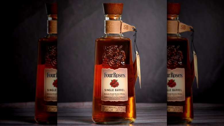 A bottle of Four Roses Single Barrel laid down and surrounded by a variety of flowers