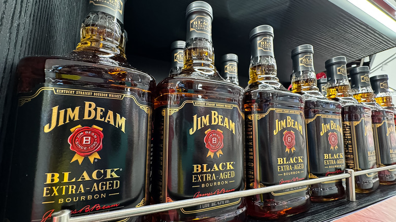 A row of Jim Beam Black bottles shown on a wooden shelf