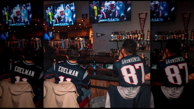 Crowd gathered around wrap-around bar watching TVs