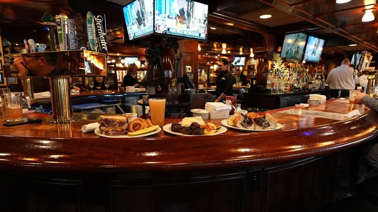 Wrap-around bar with plates of food and televisions hanging from the ceiling