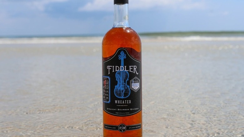 Bottle of Fiddler Wheated bourbon on beach