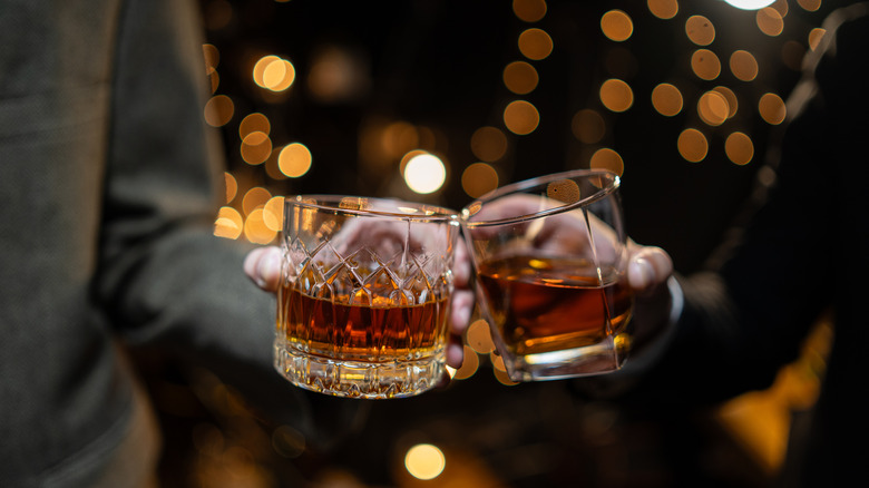 Two hands holding two different whiskey or bourbon glasses