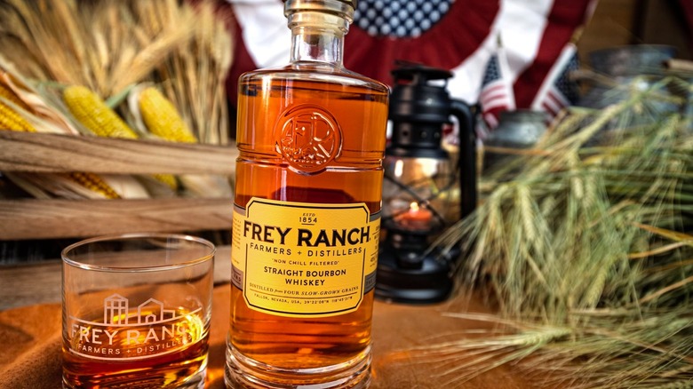 Bottle of Frey Ranch bourbon with rocks glass in front of corn