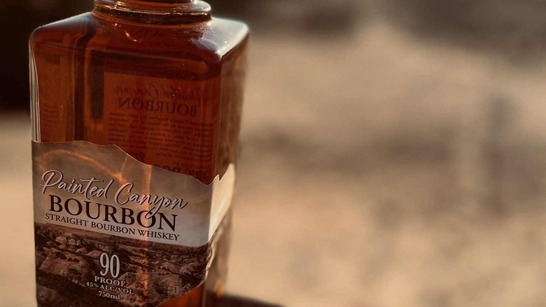 Bottle of Painted Canyon bourbon with blurred brown background