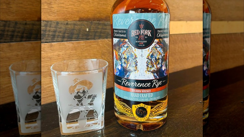 Bottle of Reverence Rye with glass and wooden background