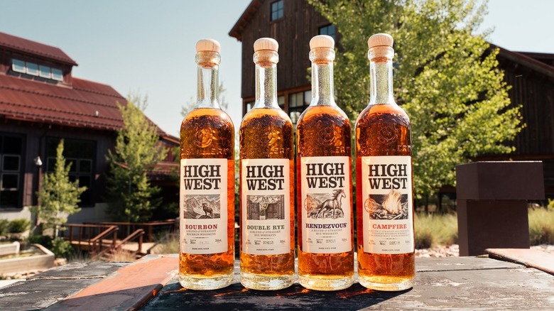 Four bottles of high West outside in front of trees and buildings