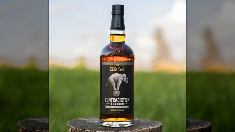 Bottle of Contradictin bourbon on tree stump outside