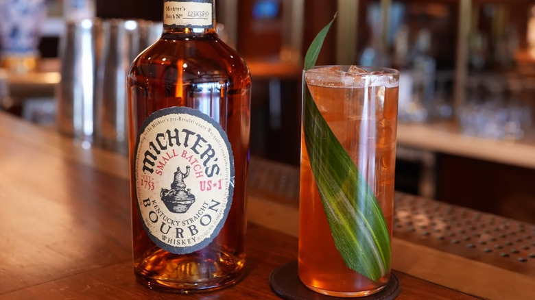 A bottle of Michter's US*1 Small Batch placed on a bar next to a highball cocktail